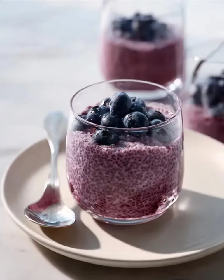 Blueberry chia seed pudding in a glass topped with fresh blueberries.