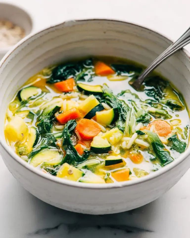 Bowl of hearty vegetable orzo soup filled with fresh vegetables and orzo pasta.