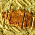 Creamy pesto sauce pasta in a bowl topped with fresh basil and parmesan