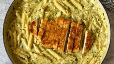 Creamy pesto sauce pasta in a bowl topped with fresh basil and parmesan